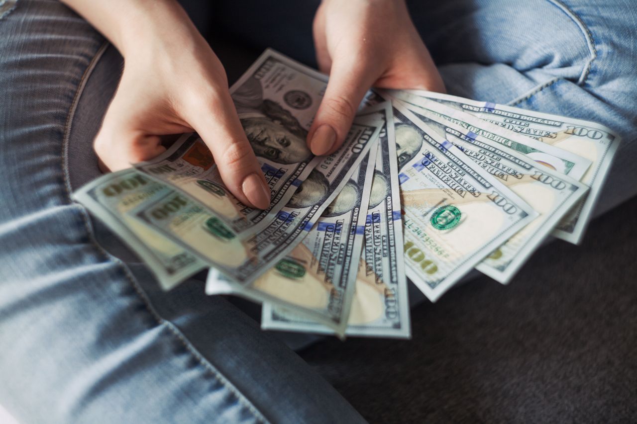 Woman holding hundred dollar bills.