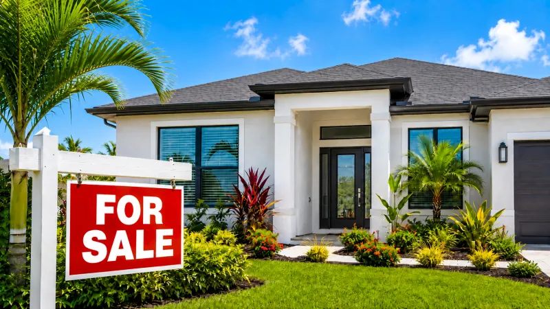 Casa moderna en el suroeste de Florida con letrero de venta y jardines tropicales